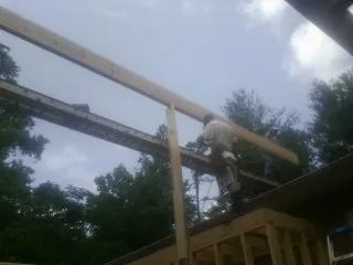 Carpenter setting a ridge beam over a new addition frame — Ice Dam Removal by Roofing Brothers in Decorah