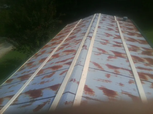 Rusted metal roof panels with new wood purlins before replacement — Storm Damage Roof Repair in Decorah by Roofing Brothers