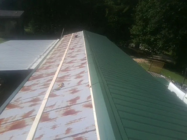 Old rusted panels beside newly installed green metal roofing — Wind Damage Roof Repair by Roofing Brothers in Decorah