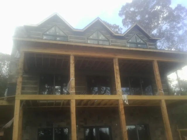 Dormers and porch framing on a large log home under construction — Roof Coating work by our crew in Decorah