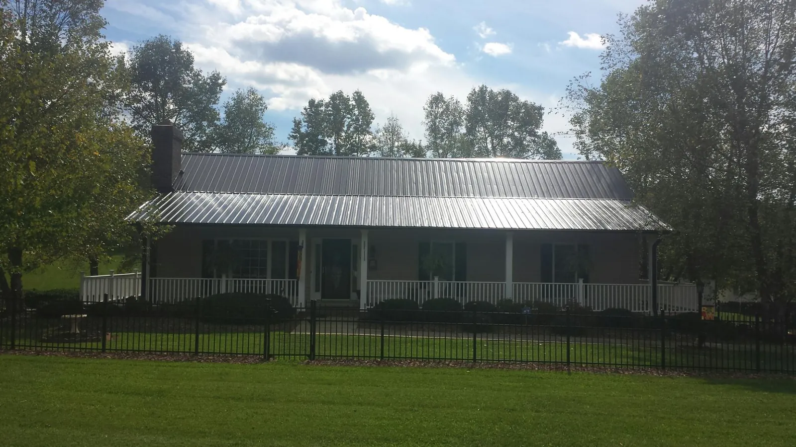 Gray metal roof on a brick ranch with a full width front porch — Gutter Guard Installation work by our crew in Decorah