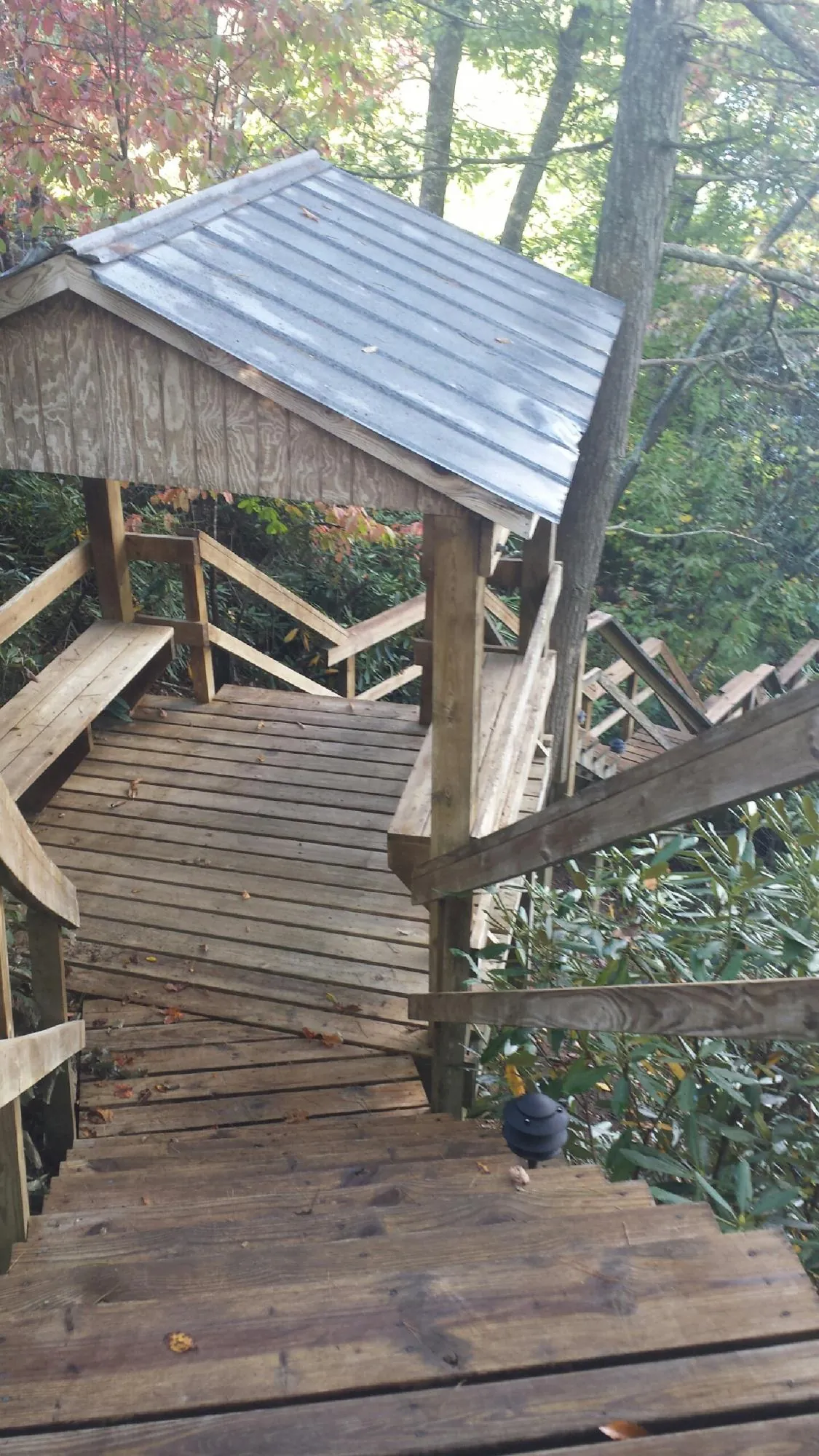 Metal roofed shelter over wooden steps on a wooded walkway — Skylight Repair & Installation work by our crew in Decorah